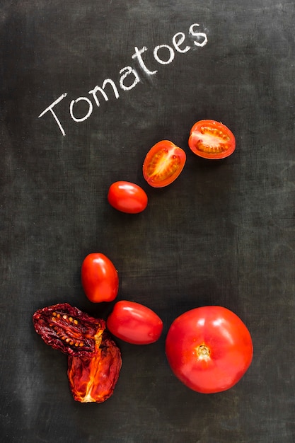 Dried and fresh organic tomatoes on blackboard over blackboard