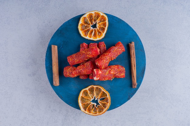 Dried fruit pulps with nuts and cinnamon sticks on blue board. 