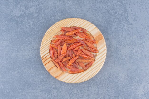 Dried fruit in the wooden plate , on the marble background. 