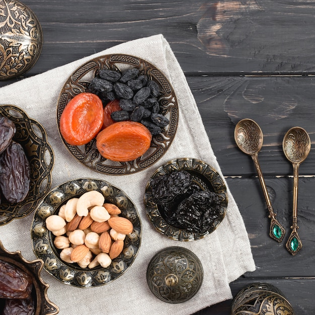 Бесплатное фото Сухофрукты и орехи; даты для рамадана с ложками на деревянный стол