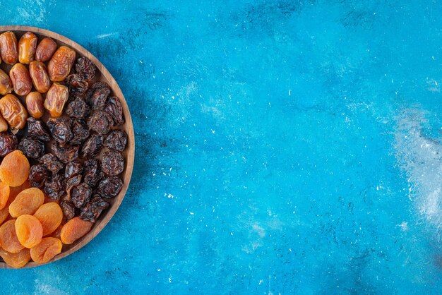 Dried fruits on a board on the blue surface