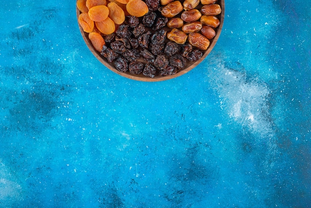 Free photo dried fruits on a board on the blue surface