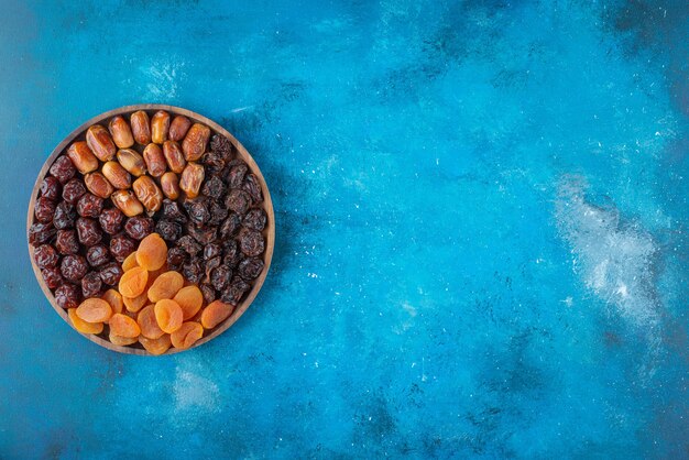 Free photo dried fruits on a board , on the blue table.