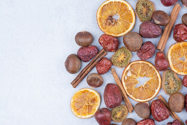 Dried fruits, cinnamon sticks and chestnut on marble surface. 