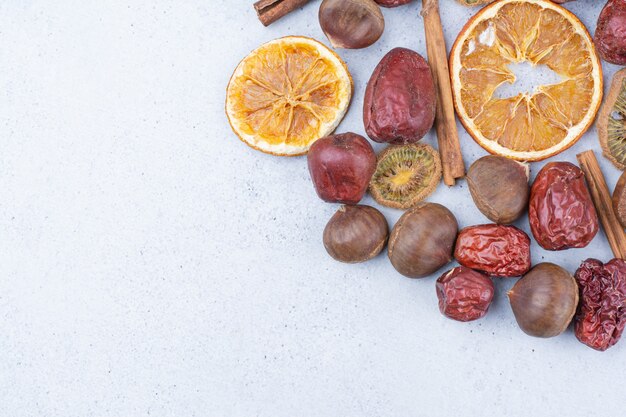 Dried fruits, cinnamon sticks and chestnuts on marble surface. 