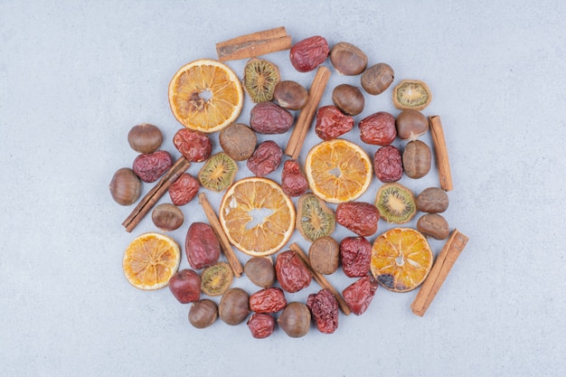 Foto gratuita frutta secca, bastoncini di cannella e castagne sulla superficie in marmo.