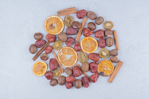 Dried fruits, cinnamon sticks and chestnuts on marble surface. 