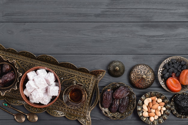 Dried fruits; nuts; dates; lukum and tea on ramadan over the wooden desk