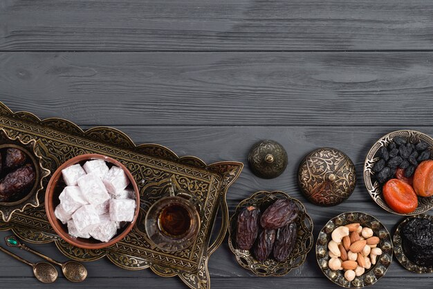 Dried fruits; nuts; dates; lukum and tea on ramadan over the wooden desk