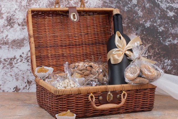 Dried fruits and nuts in wooden bag with bottle of wine.