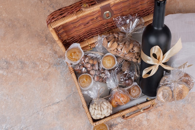 Dried fruits and nuts in wooden bag with bottle of wine.