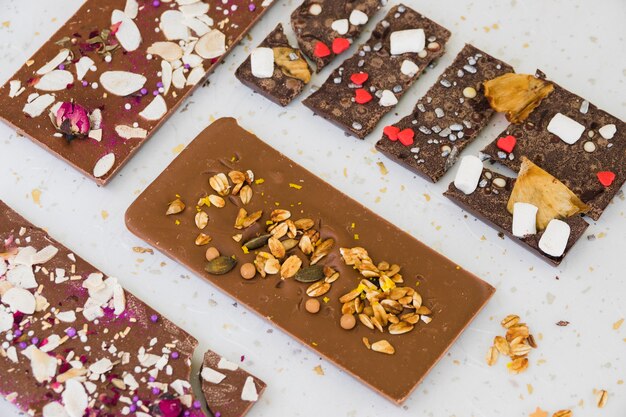 Dried fruits and sprinkles on chocolate bar against white background