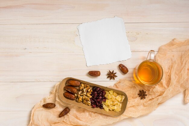 Free photo dried fruits with walnuts, paper and tea