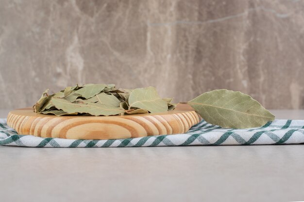 Dried green bay leaves on a wooden platter.