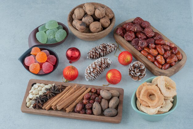 Сушеные здоровые фрукты на деревянной тарелке с елочными игрушками. Фото высокого качества