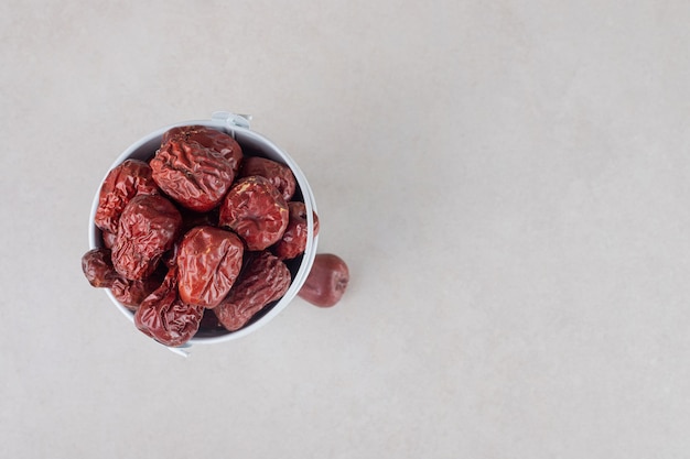 Dried indian jujube berries in a ceramic cup.