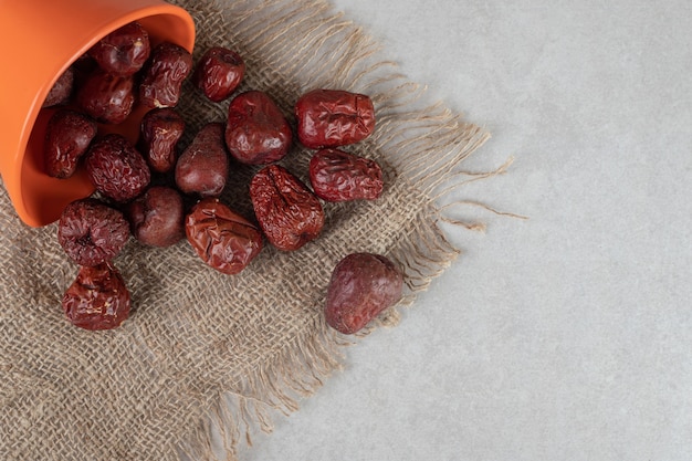 Dried Indian jujube berries in a cup on concrete.