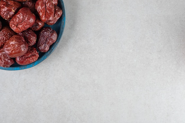 Dried Indian jujube berries in a cup on concrete.