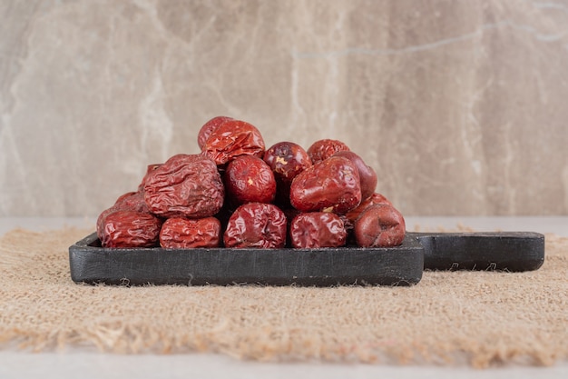 Dried indian jujube berries on a wooden platter.