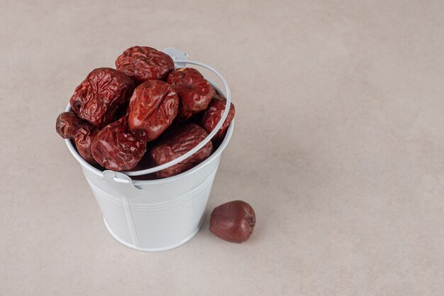 Dried jujube berries in a cup on concrete.