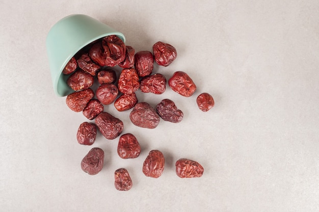 Dried jujube berries in a cup on concrete.