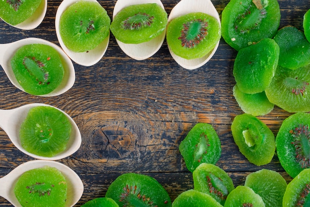 Foto gratuita kiwi secchi fette in cucchiai su sfondo di legno, piatto laici.