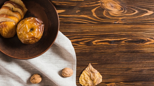 Dried leaf and nut near baked apple and cloth