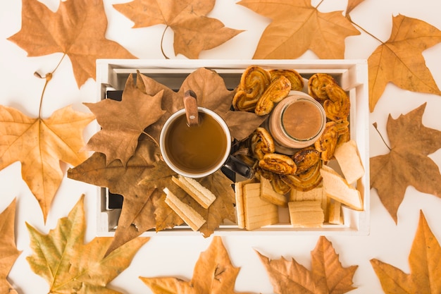 Free photo dried leaves lying around box with breakfast food