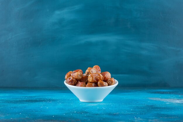 Dried oleaster in a bowl on the blue surface