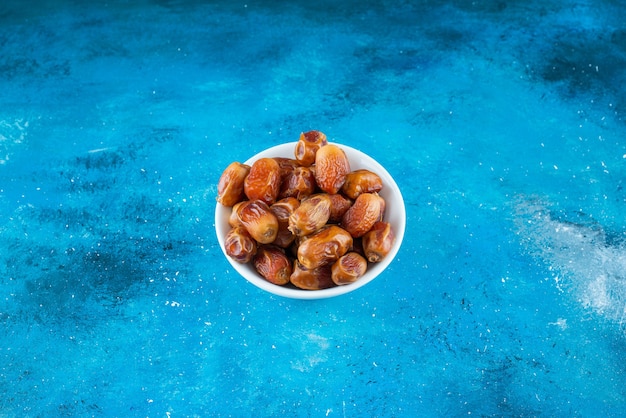Dried oleaster in a bowl on the blue surface