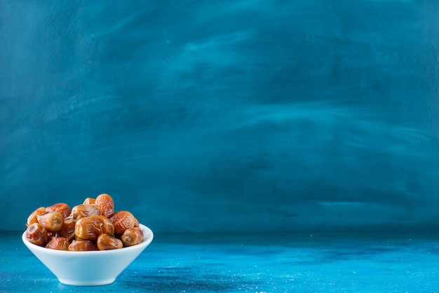 Free photo dried oleaster in a bowl on the blue surface