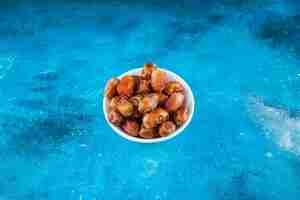 Free photo dried oleaster in a bowl, on the blue table.