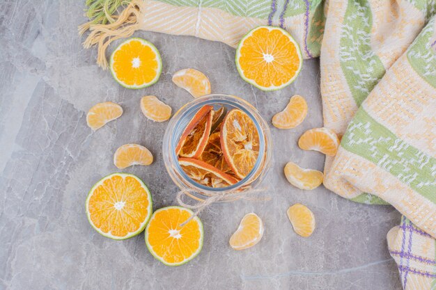 Dried orange slices in glass jar on stone surface. 