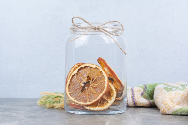 石のテーブルの上のガラスの瓶で乾燥したオレンジスライス。