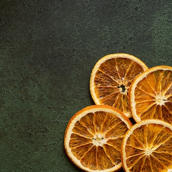 Dried orange slices on green background with copy space