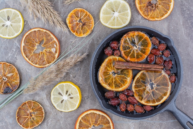 Dried orange slices, rosehips and cinnamon on black pan. 