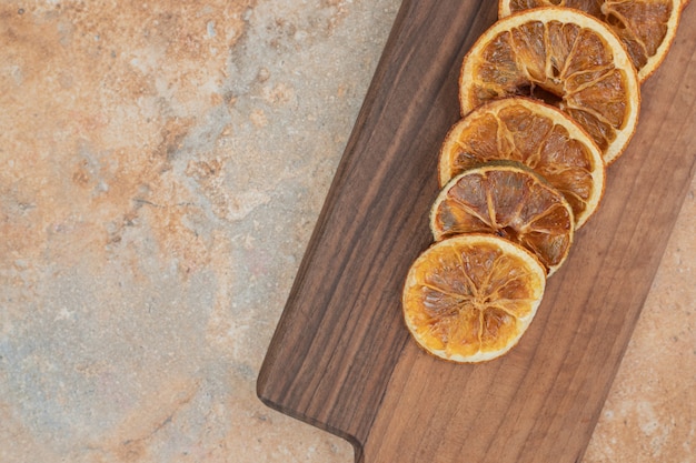 Free photo dried orange slices on wooden board.