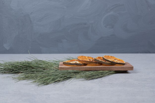 Dried orange on wooden board with branch of green tree. High quality photo
