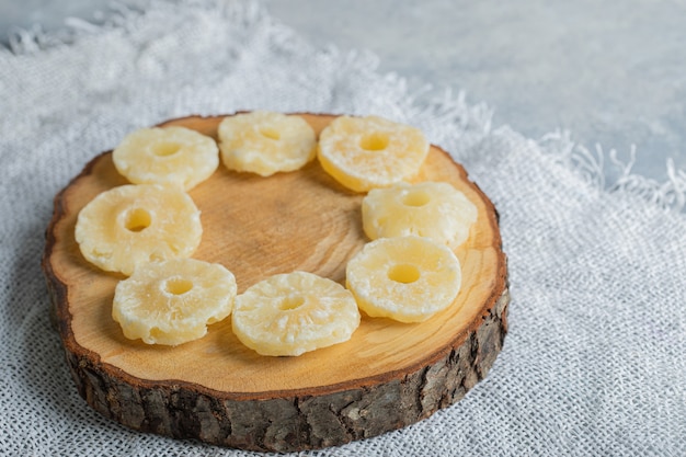 Foto gratuita anelli di ananas biologici essiccati posizionati su un pezzo di legno