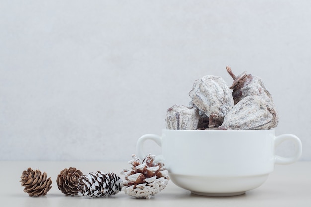 Free photo dried persimmon bowl and pinecone on beige surface