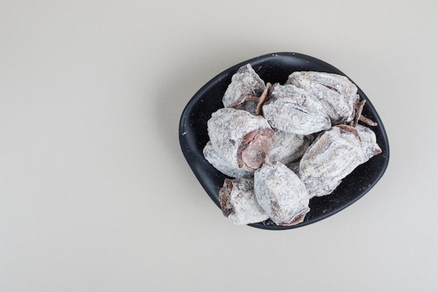 Free photo dried persimmon fruits in black bowl