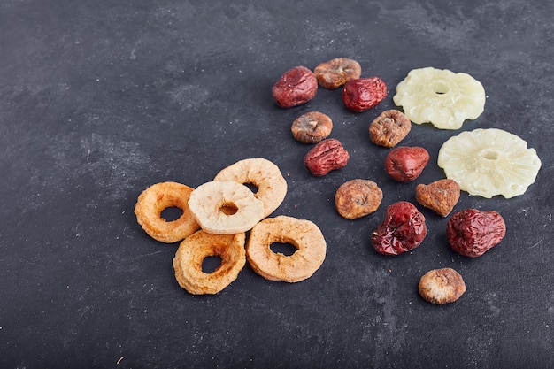 Dried pineapple, apple slices and plums on grey background . 