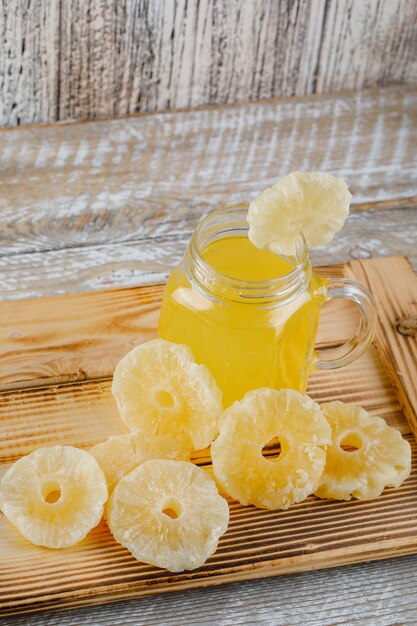 dried pineapples in a tray with juice on a wooden surface