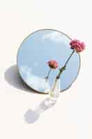 Free photo dried pink peony flower in a clear vase reflected on a mirror