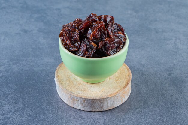 Free photo dried plum in a bowl on a board on the marble surface