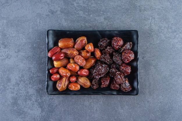 Dried plum and oleaster on a plate, on the marble surface