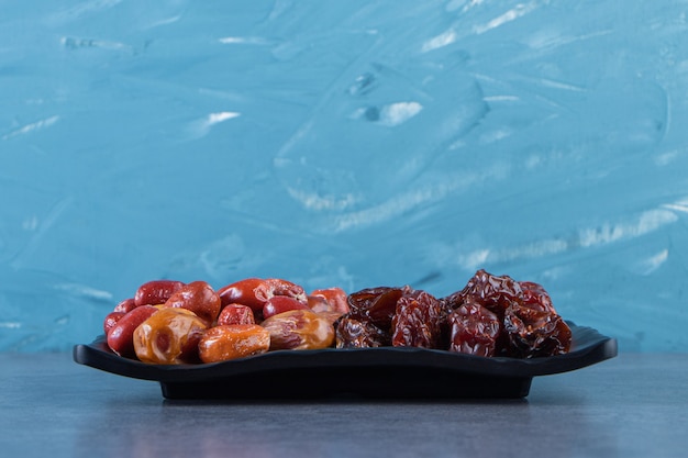 Free photo dried plum and oleaster on a plate, on the marble surface