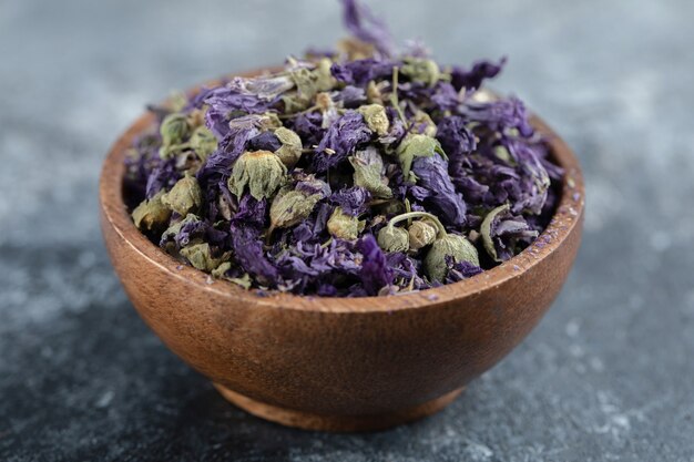 Dried purple flowers in wooden bowl.