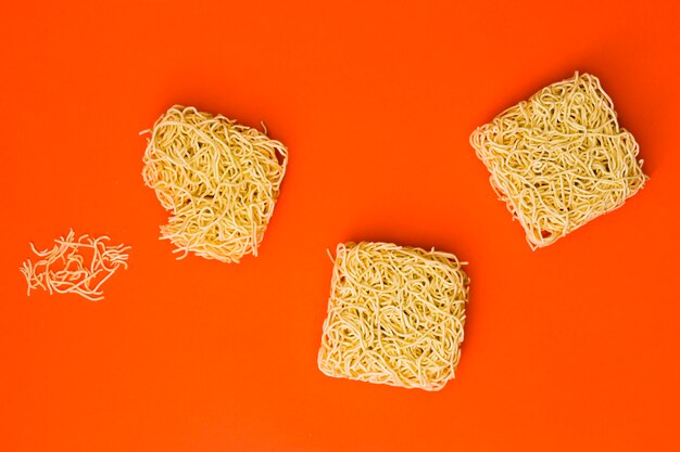 Dried raw noodles broken on orange backdrop