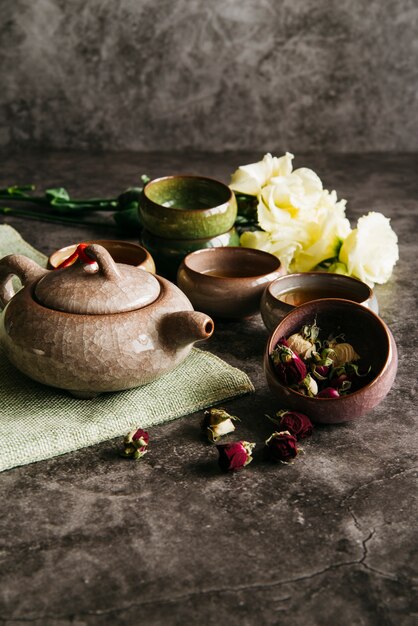 Dried rose flower with teapot; teacups and rose bouquet on concrete background